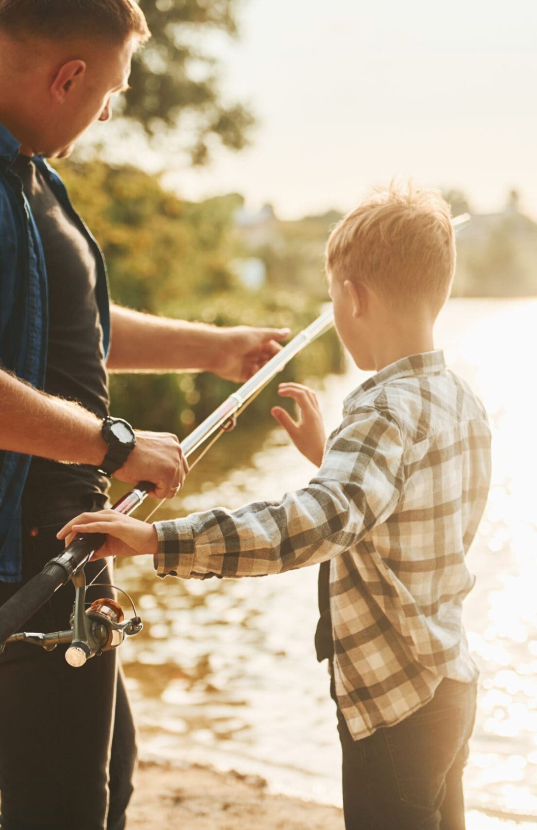 Father and son on fishing together outdoors at summertime.
