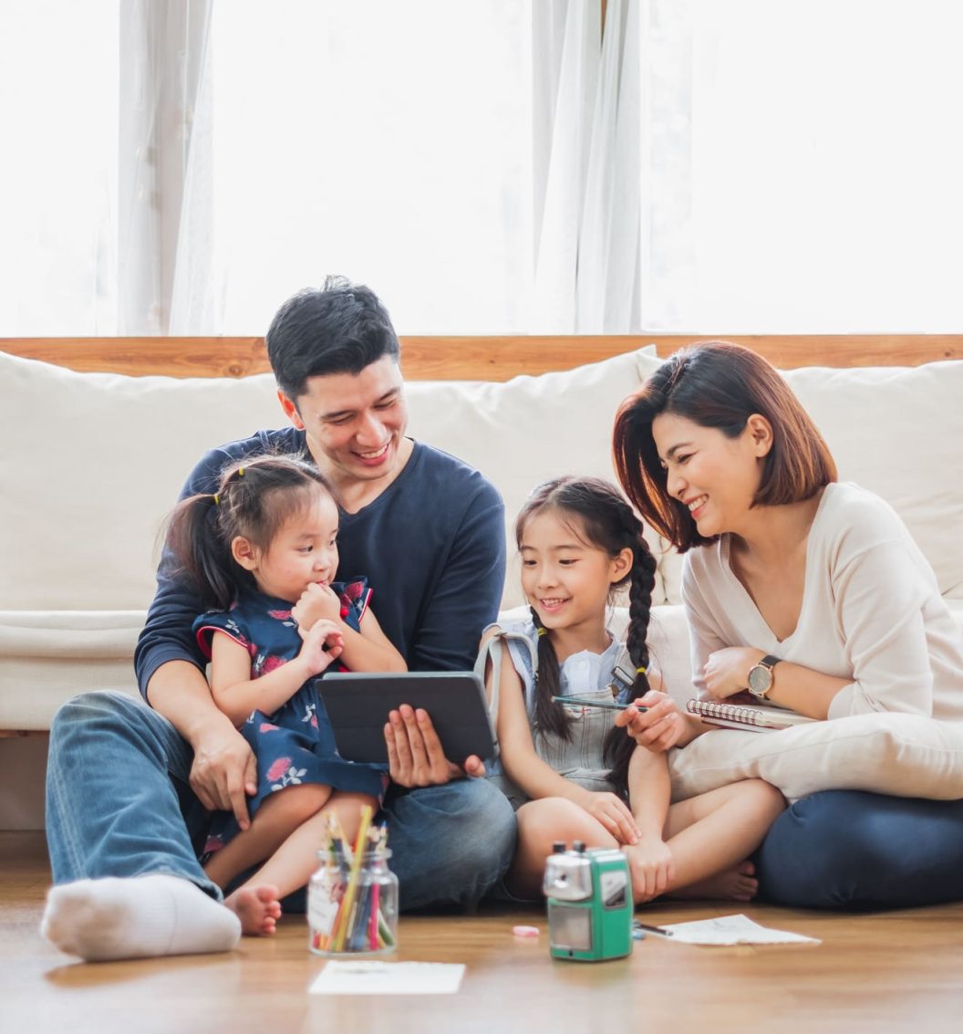 Happy Asian family using tablet, laptop for playing game watching movies, relaxing at home for lifestyle concept